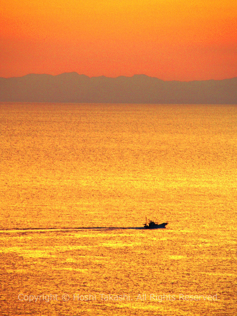 夕日の中を行く漁船